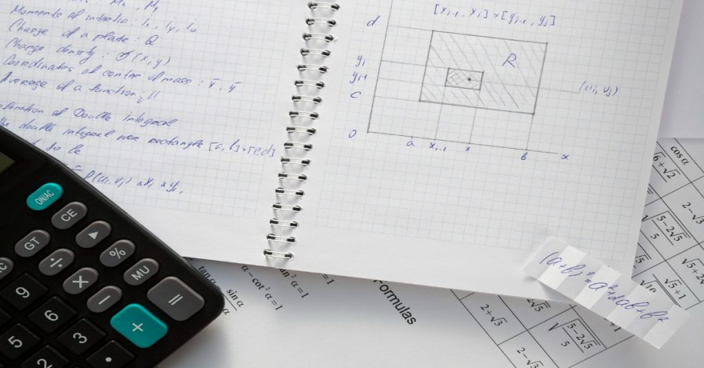 Calculator and notebook on a desk with papers, focusing on MCQs for math practice.