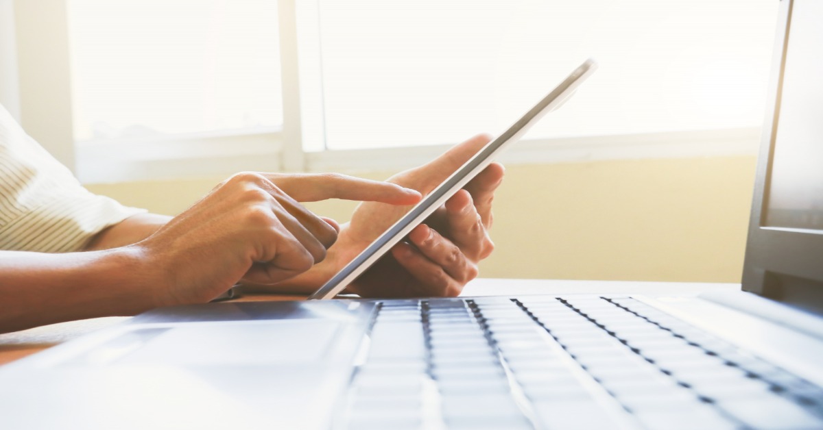 A person at a desk using a tablet computer to participate in an online survey.