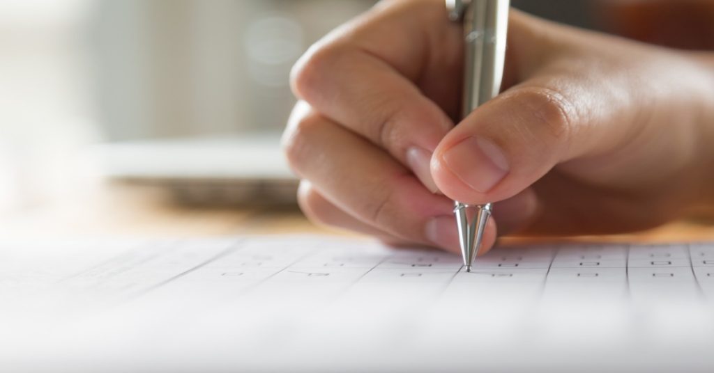 A person writing strategies and surveys on paper with a pen, focusing on perfecting their opening act.