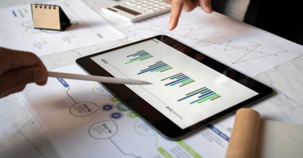 Business professionals analyzing survey data on a tablet.