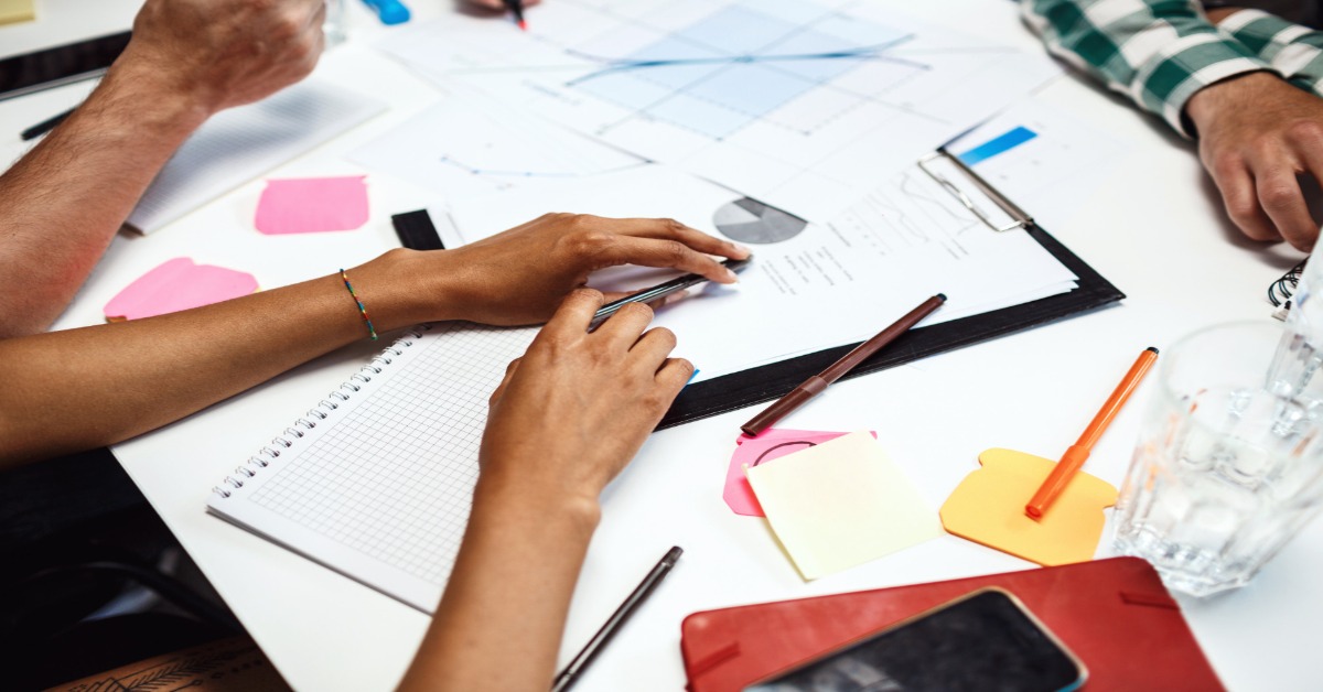 individuals engaged in survey design, working together at a table filled with papers and stationery.