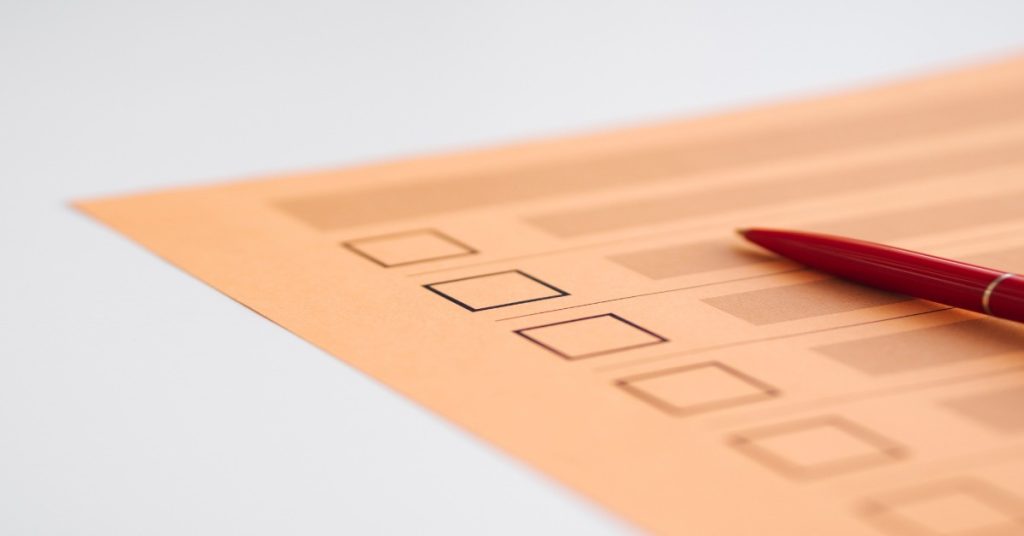 Red pen on an orange paper checklist, emphasizing question types concerning why individuals abandon surveys.