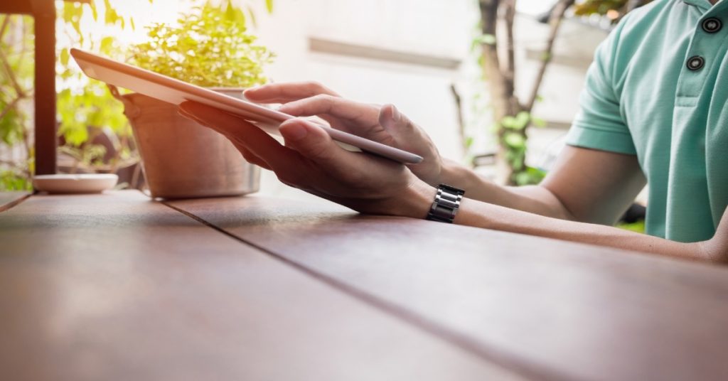 A man at a table using a tablet to fill a survey for communication